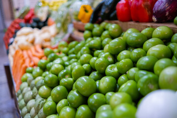 Colorful vegetables stand with green tomatoes, carrots, potatoes, and more