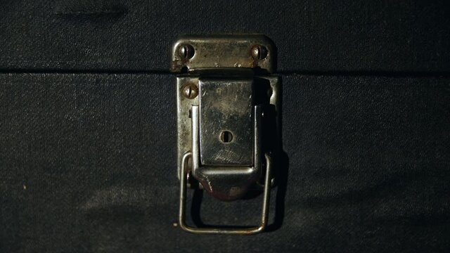 Caucasian man hand opens old vintage metal rusty lock on dirty antique suitcase