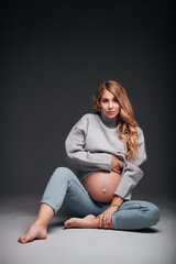 Young beautiful pregnant woman sitting on black background