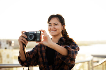 Attractive tourist with a camera. Beautiful woman with camera taking photos of beautiful location