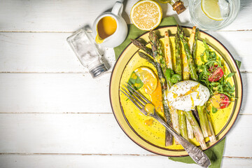Healthy food, baked grilled asparagus, poached egg and hollandaise sauce on white wooden background copy space top view