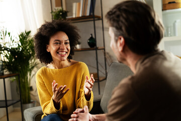  Young couple sitting and talking at home. Woman and man flirting and laughing.