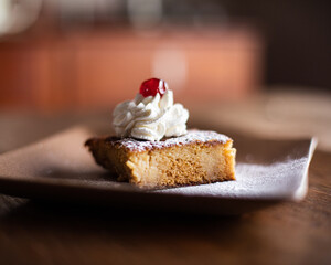 Dessert with cream and red cherry on brown plate