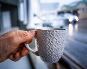 Cup of coffee held up on a cold morning with street in the background