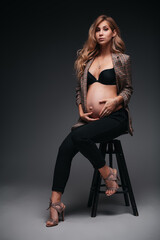 Obraz na płótnie Canvas Young beautiful pregnant woman in jacket on black background