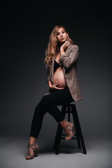 Fototapeta na wymiar Young beautiful pregnant woman in jacket on black background