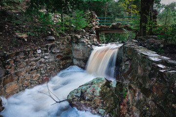Fast flowing waterfall under an old bridge