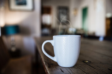 Steaming cup of warm beverage on old wooden table in stylish house