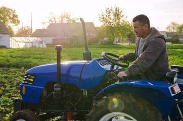 A farmer on a tractor drives across the farm field. Agro industry, agribusiness. Potato harvest campaign. Farming, agriculture. Harvesting potatoes in early spring. Countryside farmland.