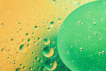 oil with bubbles on vibrant green and yellow background. Abstract space background.
