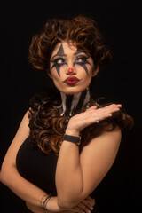 Woman with brown hair and painted face. Joker makeup. Pursed lips. Closeup of face