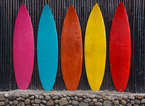 Colored Surfboards Leaning Up Against A Wooden Fence