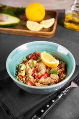  Salmon salad with tomatoes, avocado and quinoa in a blue bowl on a dark gray table vertical photo, a dish of balanced diet