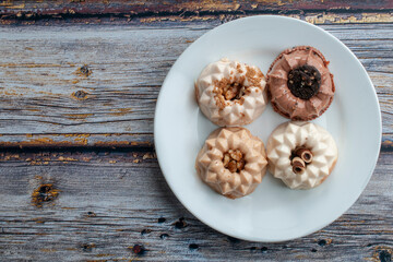 Flat lay dessert ,chocolate flan, vanilla flan, piña colada flan and coffee flan evaporated milk or condensed milk on a white plate over a rustic table