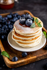 Homemade pancakes with blueberries and powdered sugar on the table close-up vertical photo