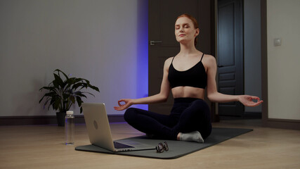 The girl presses the play button on the laptop and begins to meditate