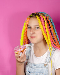girl with colored dreads and sweet donut on pink background