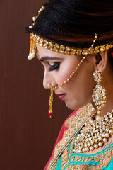 Indian model wearing traditional Maharashtrian bridal green sari and jewelry. Looking down. Face close-up