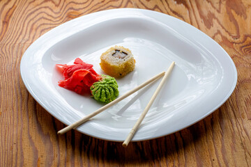 baked sushi with eel wasabi ginger and chopsticks on a white plate