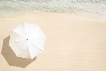 White umbrella on tropical sand beach. Top and aerial view. Ocean coastline. Drone photo. Background