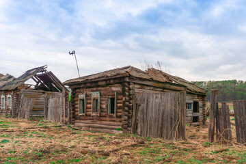 Old ruined uninhabited rustic wooden houses made of logs sunny day