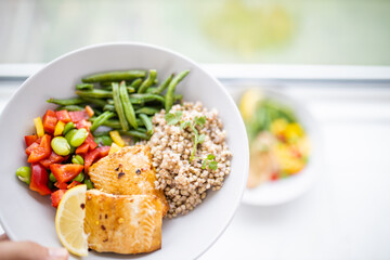 Hand holding salmon and buckwheat dish with green beans