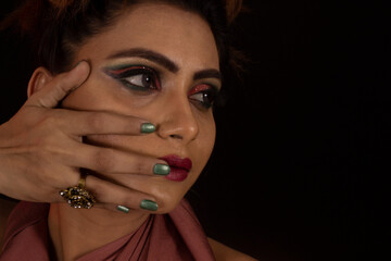 Obraz premium Portrait of young girl looking away from camera. Hands on face. Black background. Closeup of face.