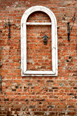 Wall texture of old red brick with white window frame and metal fittings, straight view