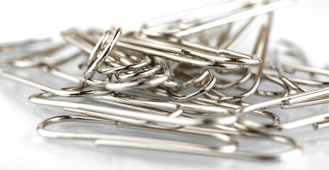 Bunch of steel metal paper clips on a white background
