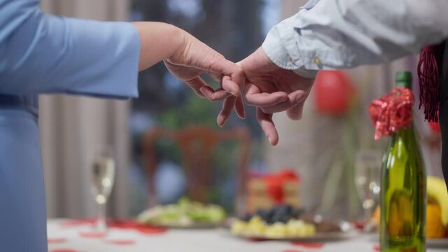 Male and female hands holding little fingers on Valentine's day indoors. Pinky swear of unrecognizable Caucasian loving man and woman on holiday or anniversary. Trust and promise concept