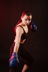 Strong sport woman boxer wearing blue boxing gloves on dark red background