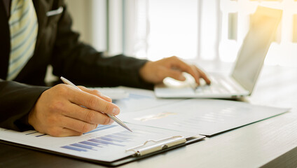 Business analysts create graphs of investment costs, real estate and other tax systems on their desks with laptops.