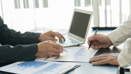 Business analysts create graphs of investment costs, real estate and other tax systems on their desks with laptops.