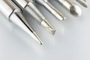 Close-up of soldering tips on glass table, silver background with equipment for soldering iron