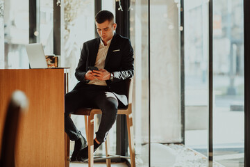 Happy business man sitting at cafeteria with laptop and smartphone.