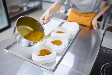 A bright girl cooks sweet dishes at a small production facility