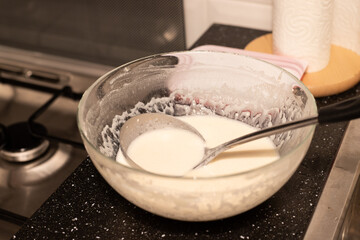 Fototapeta na wymiar Preparation of the mass for pancakes. Mixed milk with flour in a bowl.
