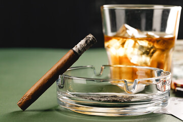 Close up of smoking cigar and whiskey glass on table