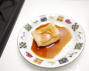 焼いた餅を醤油に浸している