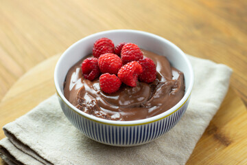 Chocolate pudding with raspberries on a wooden table.