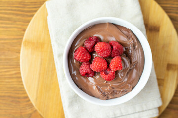 Chocolate pudding with raspberries on a wooden table.