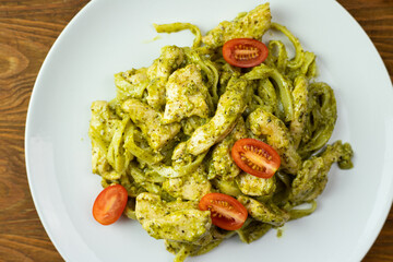 Pasta with pieces of chicken, basil pesto, and tomatoes. Delicious dinner.