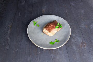 juicy beef steak with grill stripes on gray plate with parsley on black table