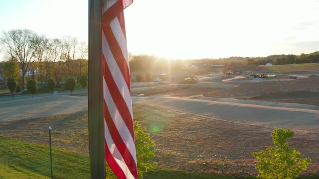 American flag during sunrise, sunset. Ground is prepared for new home construction site, housing expansion development in USA.