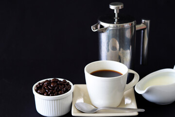 set of coffee, milk and french press coffee maker on black background with copy space