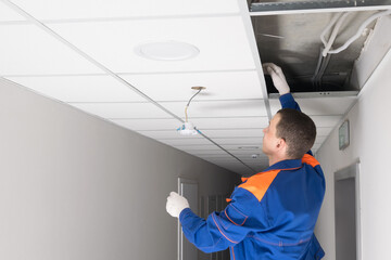 a worker is installing a lighting fixture in the ceiling, side view