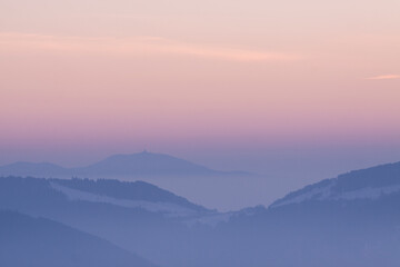Obraz premium Mountain panorama at sunrise with clouds fog and pink sky