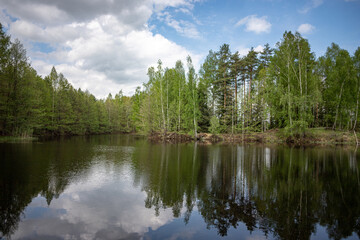 Fototapeta na wymiar Forest lake view, smooth surface of a lake with clouds reflected, shining level of a forest lake