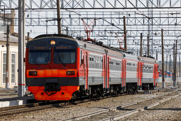 The electric train is red at the station in the daytime.