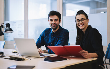 Happy coworkers preparing report together in office